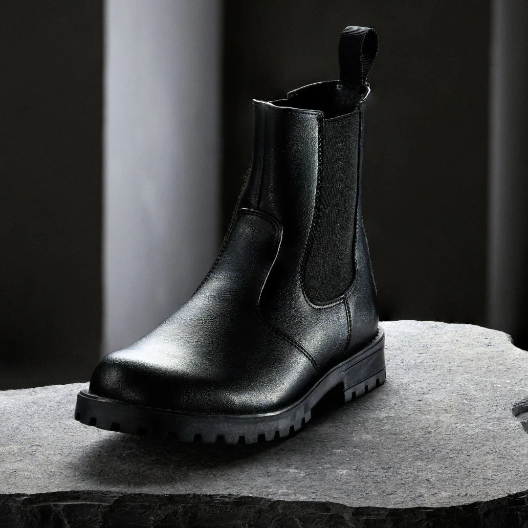 Black leather boot on a gray surface with a dark background