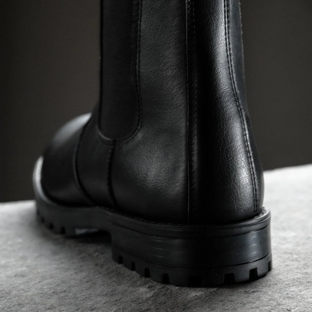 Black leather boot on a gray surface with a dark background