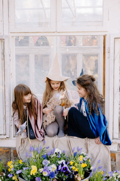 Pretend play scene: Toddler in a Rose Gold cat costume near a crib