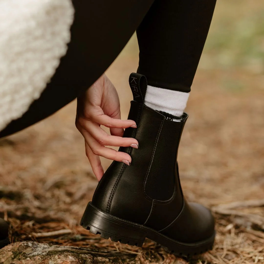 Person wearing a black boot with a blurred natural background