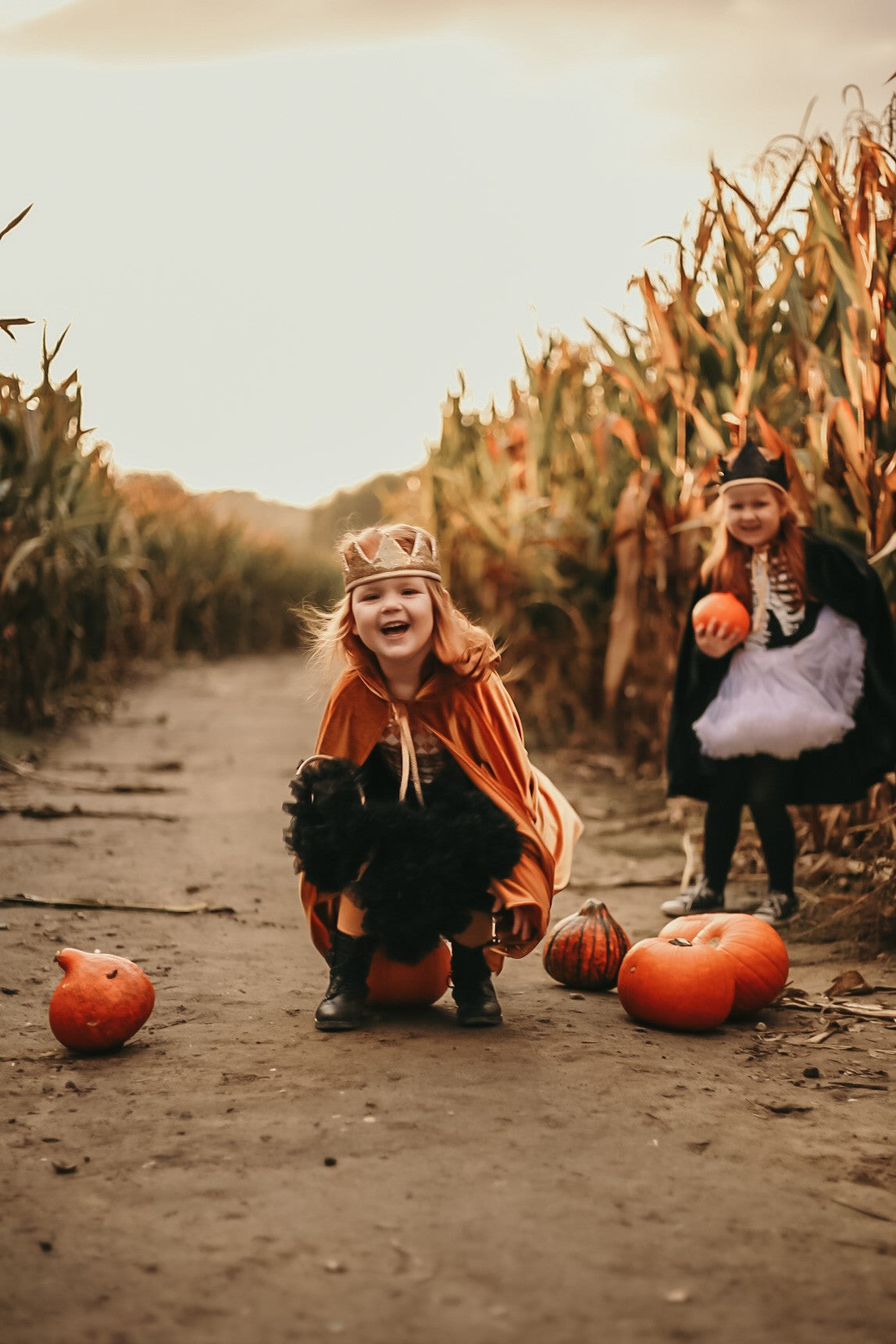 Moi Mili Magic Cape: two kids in warm velvet costumes playing amongst pumpkins on a sunny autumn afternoon