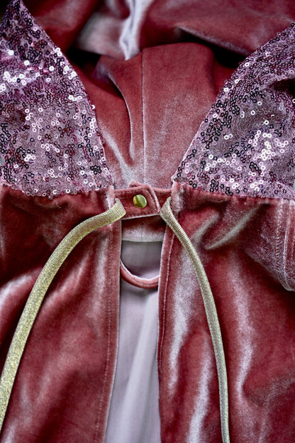 Detailed view of the pink velvet fabric and secure snap fastening on the cape