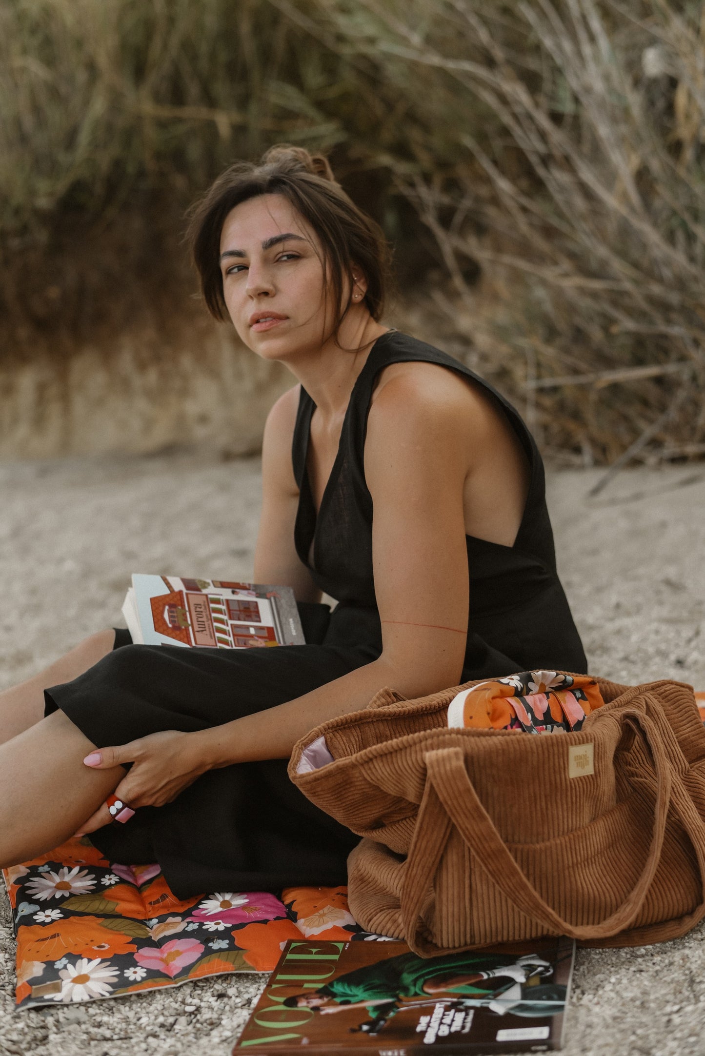 Moi Mili Mom Weekender Bag Caramel: a mother resting on the grass while reading a book in natural surroundings