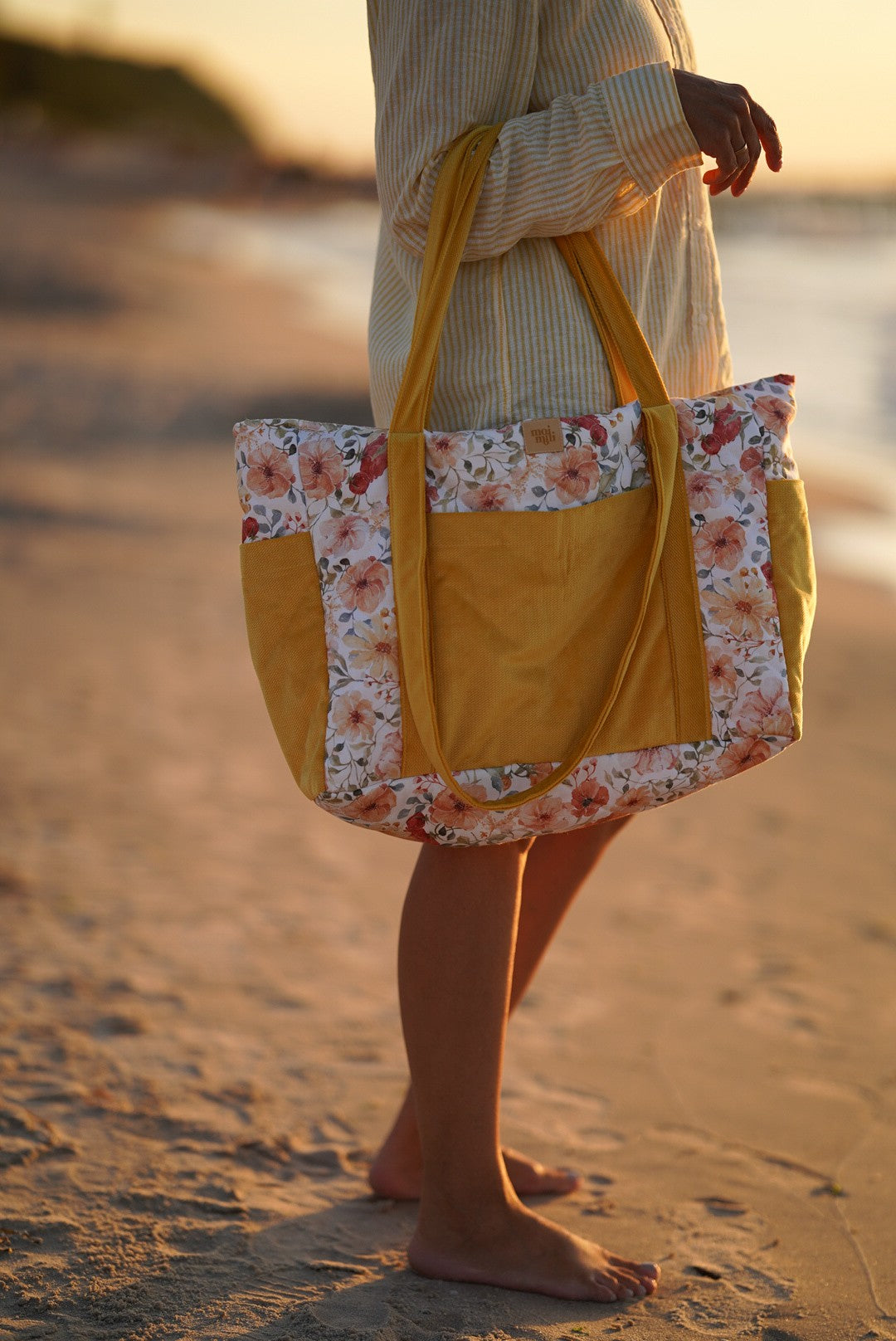 Moi Mili Flower Power Mom Weekender Bag: a mother standing by the ocean at sunset holding a large floral cotton bag
