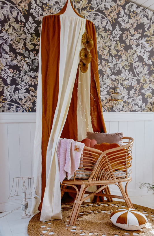 Boho kids room: Caramel Circus organic cotton canopy styled with natural rattan decor