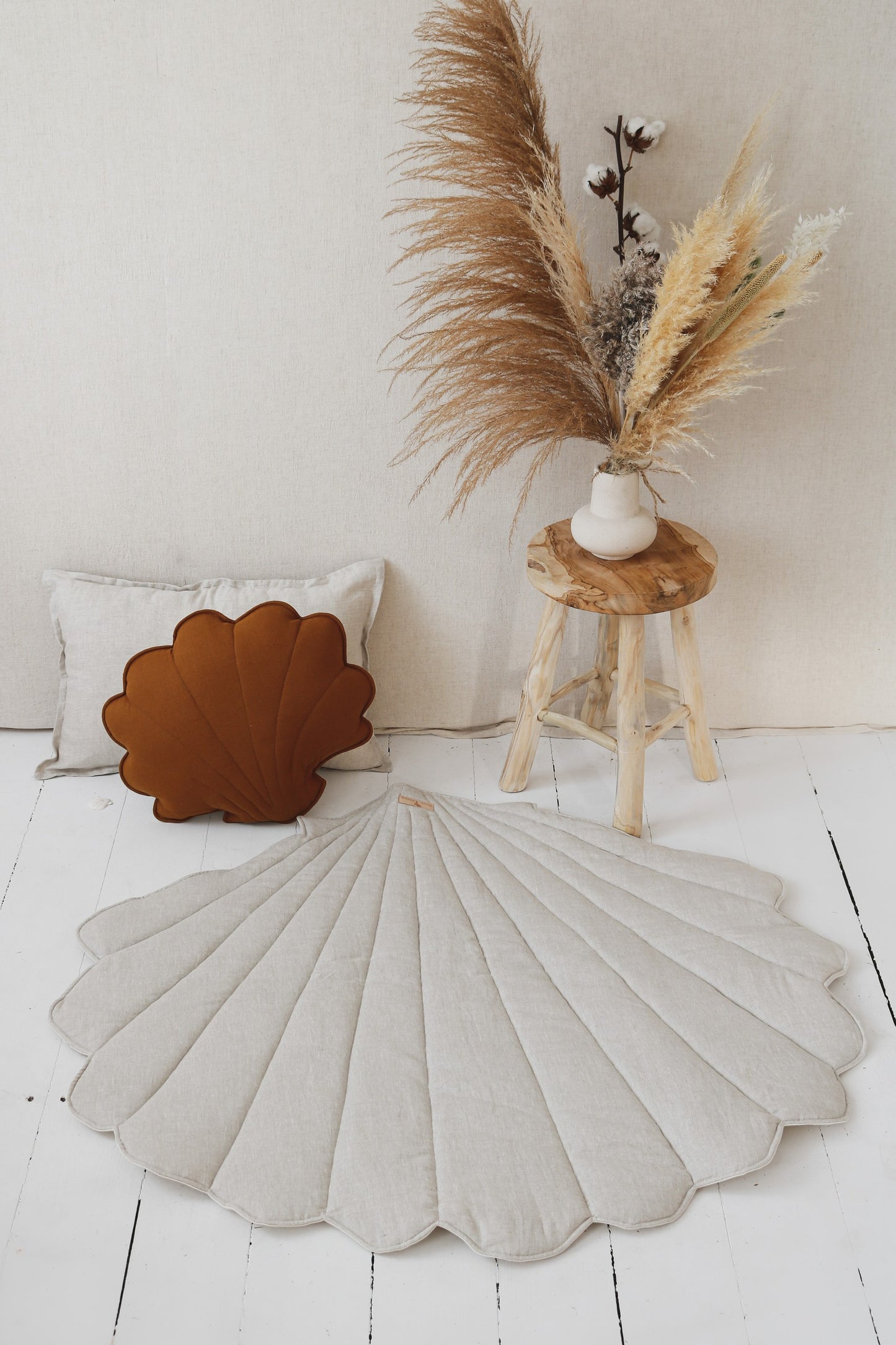 Boho nursery: Sand shell mat on a natural wood floor next to a linen canopy