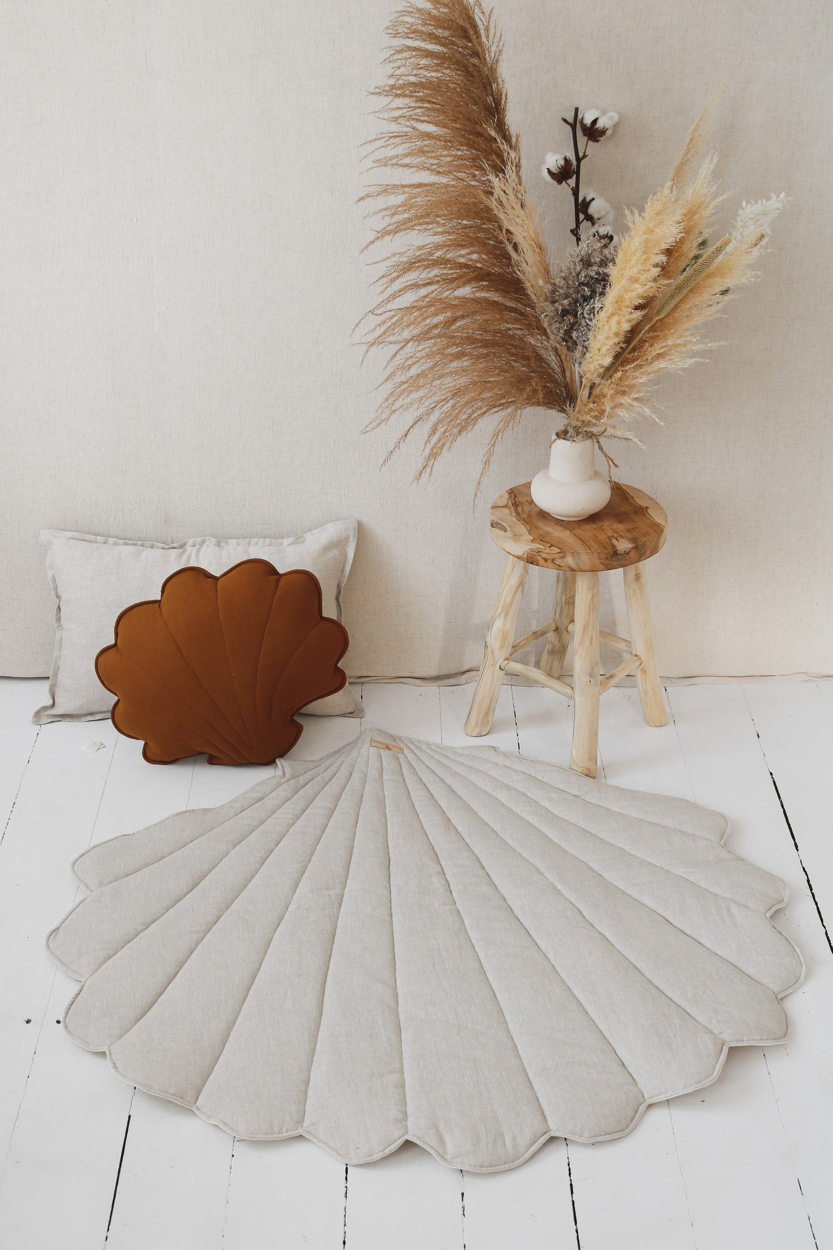 Boho nursery: Sand shell mat on a natural wood floor next to a linen canopy
