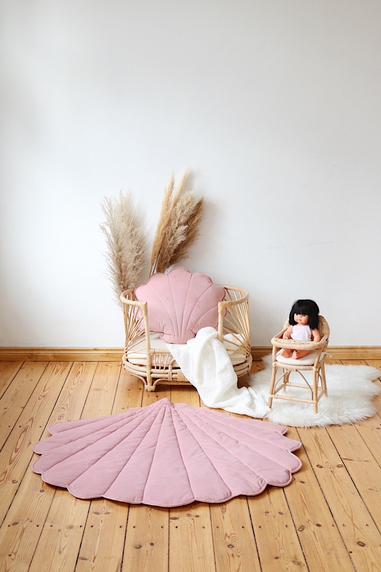 Cozy nursery decor: a wooden baby crib and vintage high chair featuring a Moi Mili Powder Pink Velvet Shell Playmat on the floor