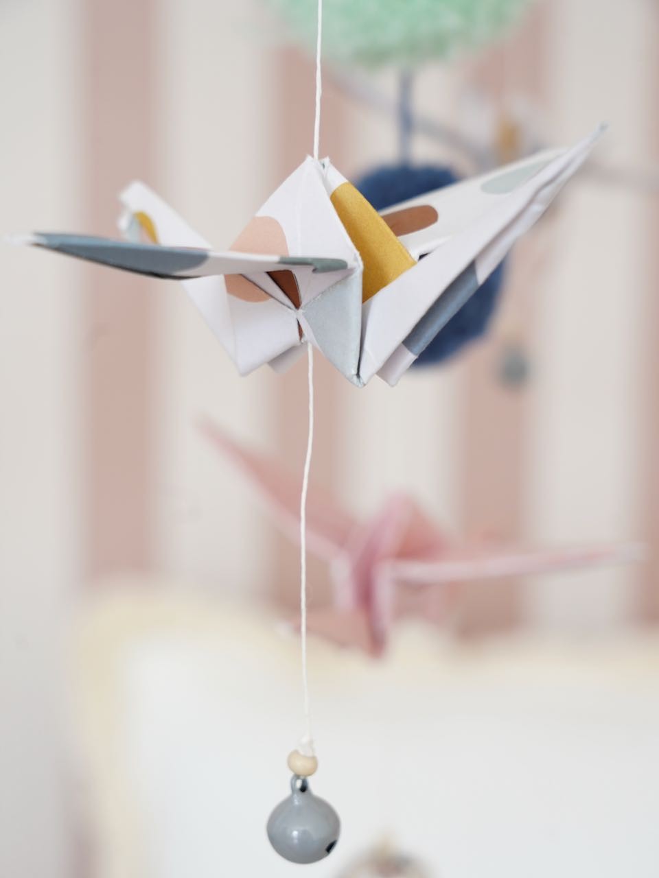 Detailed view of the soft pastel fabric and geometric origami folds of the nursery mobile