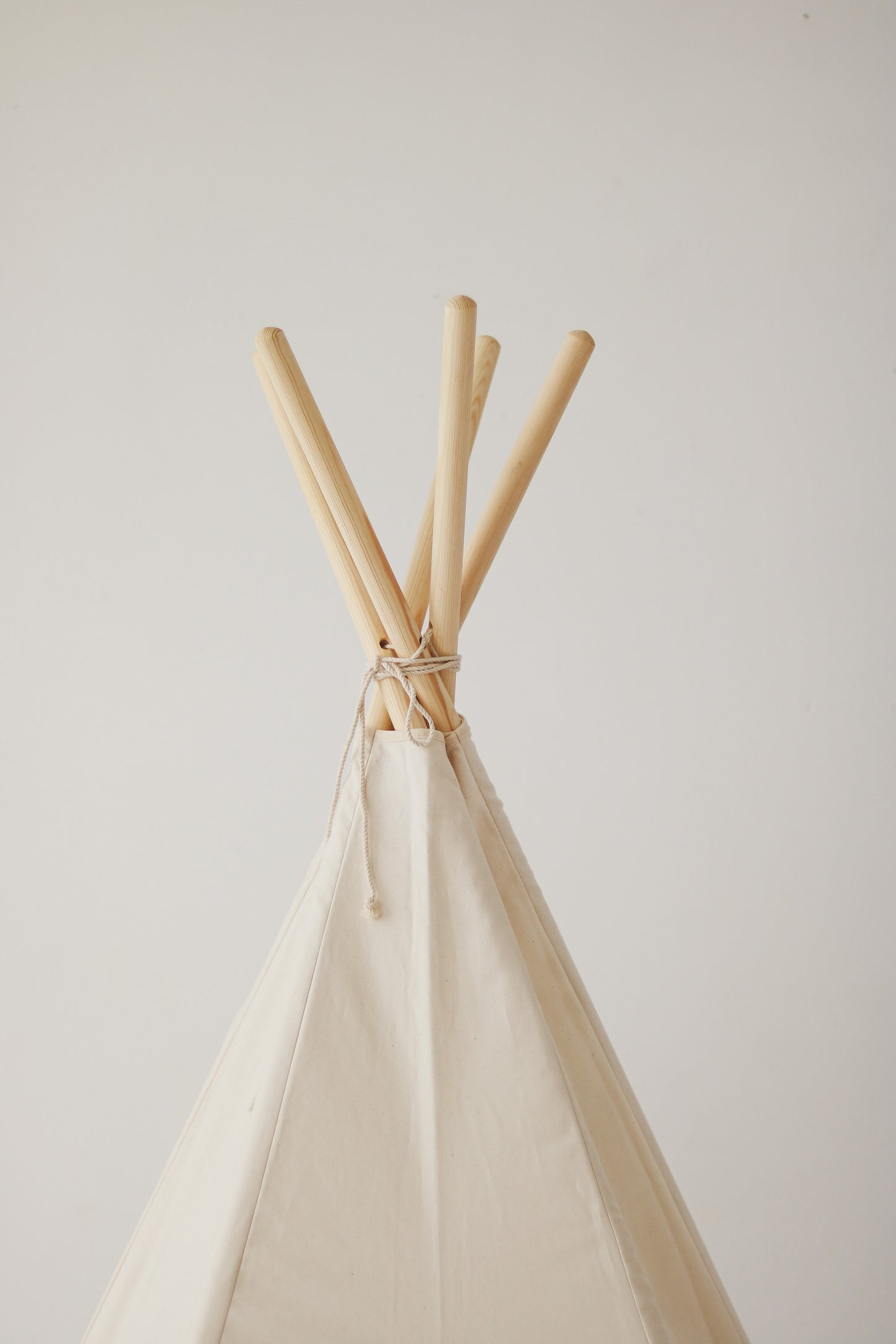 Close-up of the reinforced stitching and natural pine poles of the minimalist beige teepee