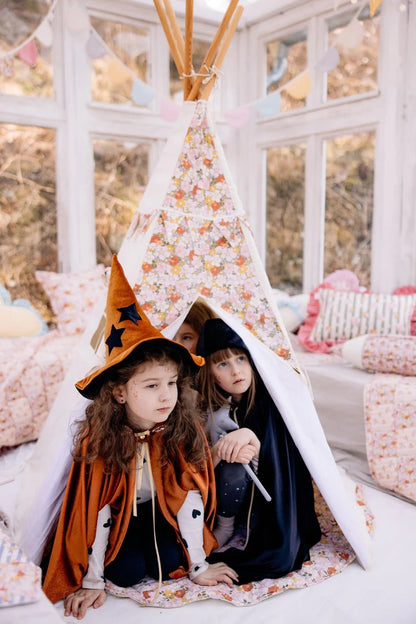 Cozy hideout: a close-up of three girls sharing secrets and laughing safely inside a high-quality green canvas teepee tent made of OEKO-TEX certified cotton