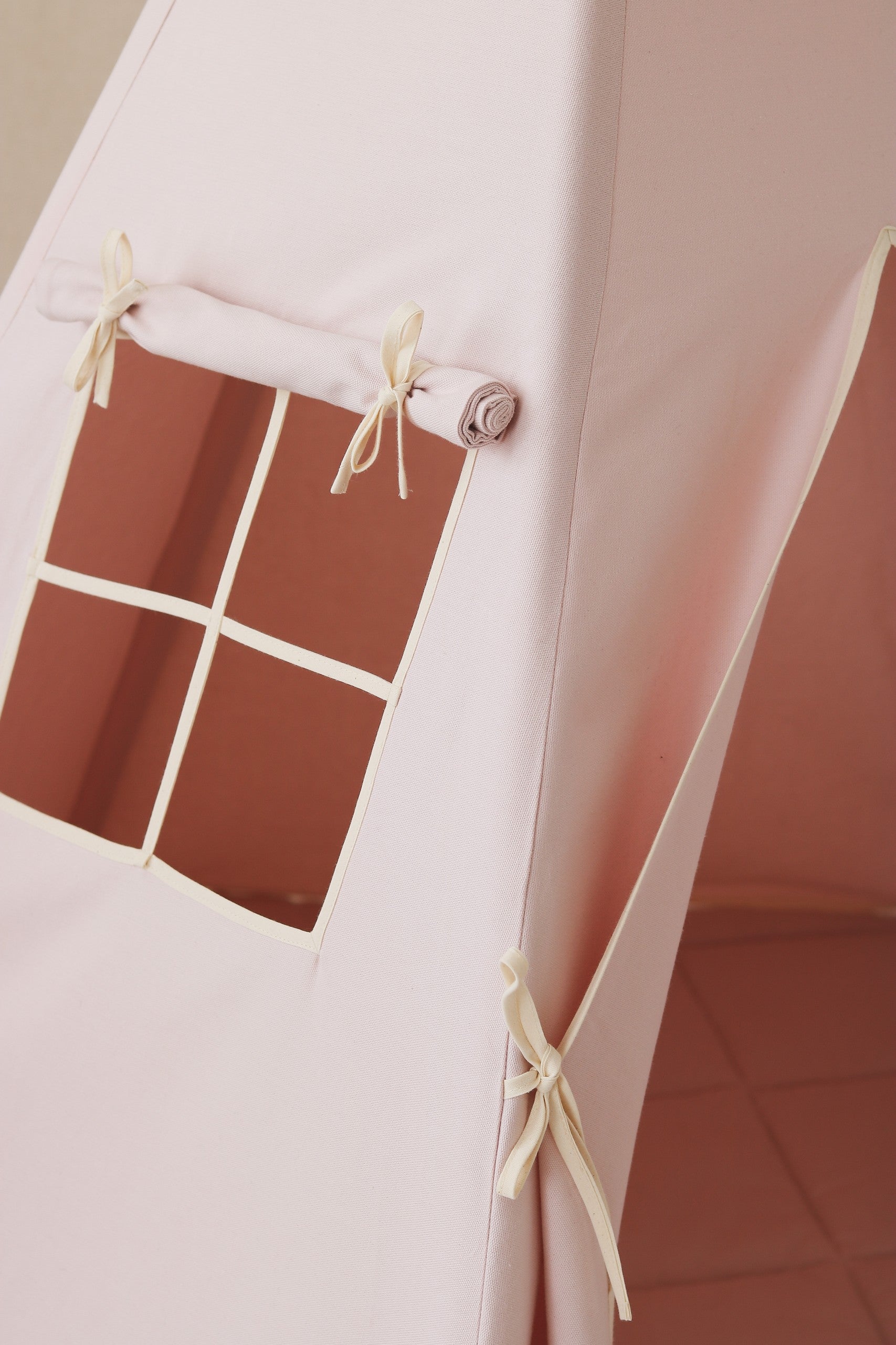 Nursery detail: close-up of the charming side window on a Moi Mili Pink Teepee Tent, letting soft natural light into the dusty pink play space