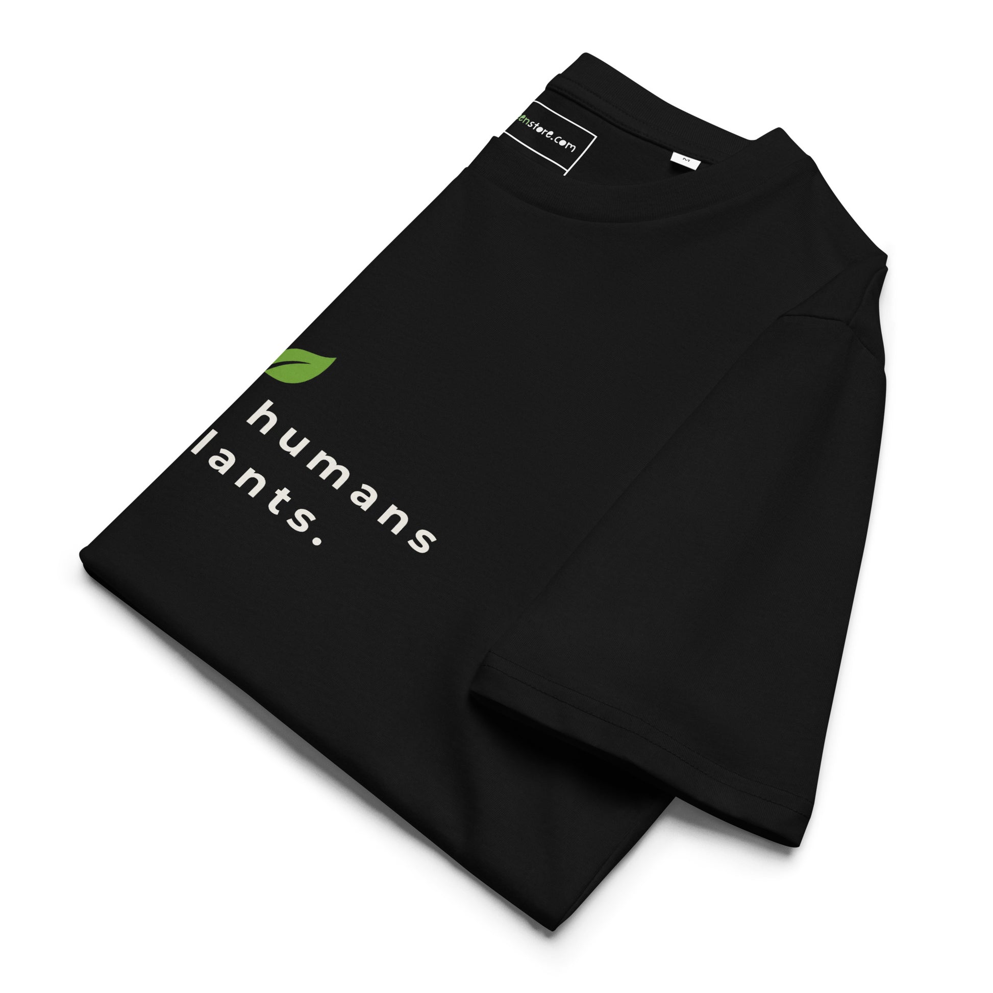 Sustainable black t-shirt neatly folded on a flat surface, with the leaf logo and the "raising humans on plants." message clearly visible on top.