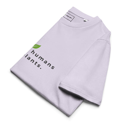 Sustainable t-shirt neatly folded on a flat surface. The top of the folded fabric displays the leaf logo and the "raising humans on plants." message designed for plant-based parents. -lavander-