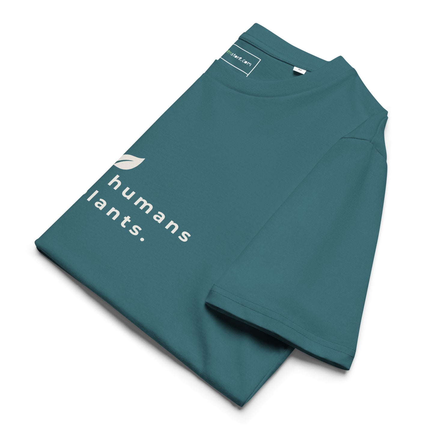 Sustainable t-shirt neatly folded on a flat surface. The top of the folded fabric displays the leaf logo and the "raising humans on plants." message designed for plant-based parents. -stargazer-